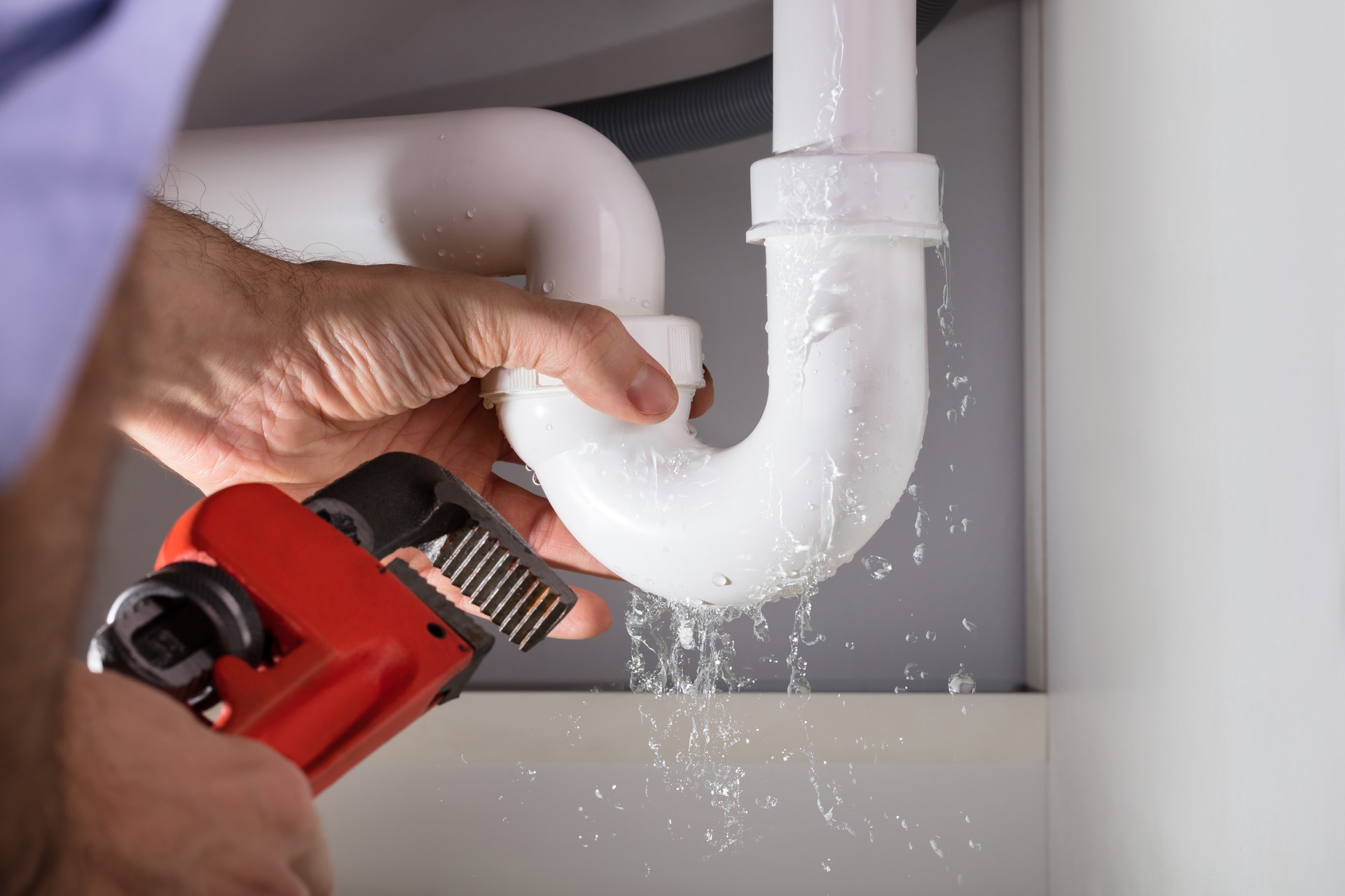 Plumber Fixing Sink Pipe With Adjustable Wrench